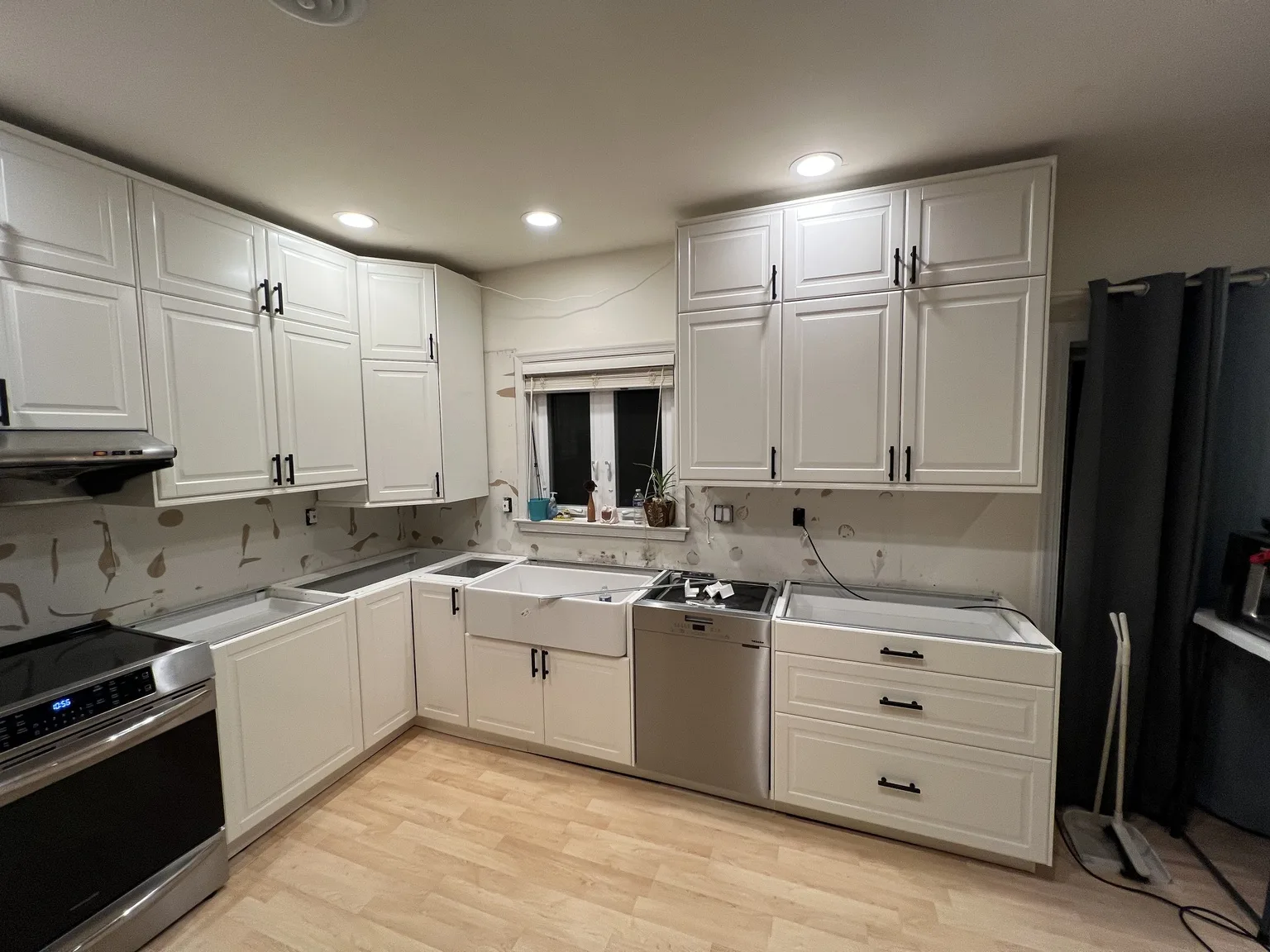 White U-shaped IKEA kitchen with black handles and farmhouse sink